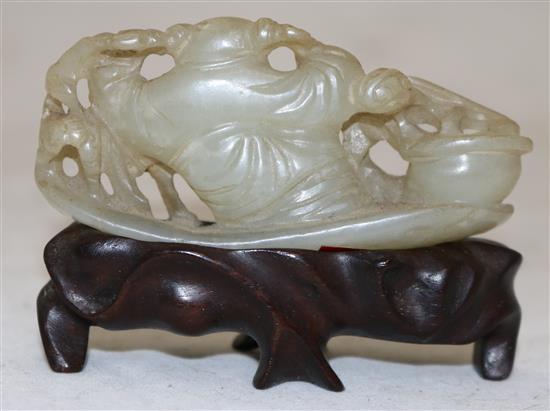 A Chinese pale celadon jade carving of a boy seated on a pine raft, 18th/19th century, 7.1cm, rosewood stand